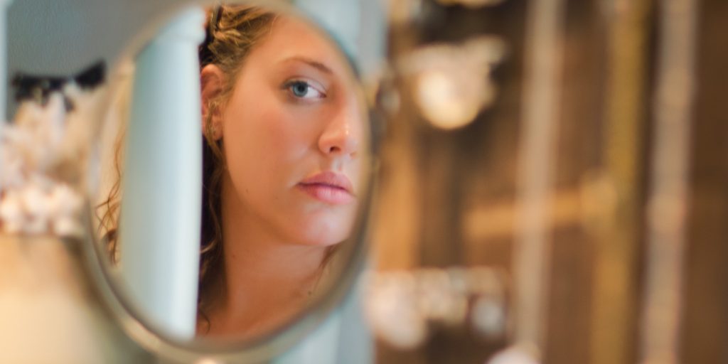 Young woman looking at herself in the mirror